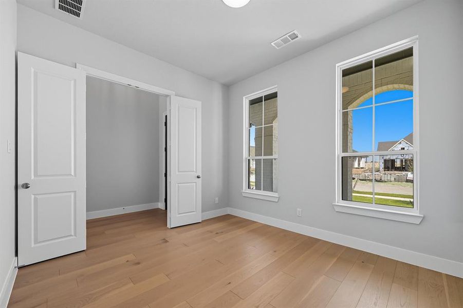 Unfurnished bedroom featuring multiple windows and light wood-type flooring
