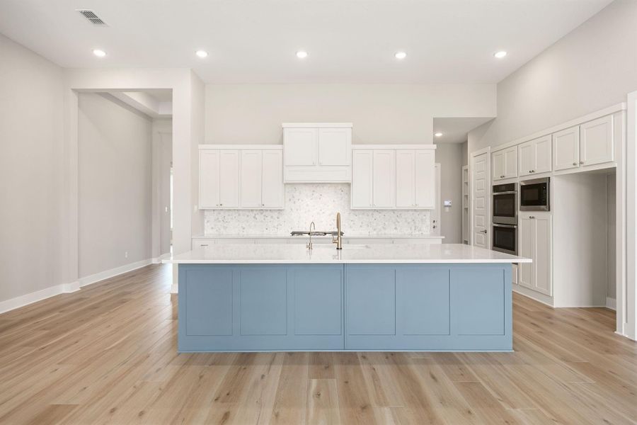 The gourmet kitchen showcases a generous quartz-topped island in a striking blue finish, complemented by crisp white cabinetry and a mosaic tile backsplash. The gourmet kitchen showcases a generous quartz-topped island in a striking blue finish, complemented by crisp white cabinetry and a mosaic tile backsplash.