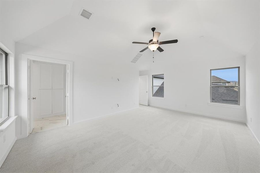 Spare room featuring vaulted ceiling, light carpet, and a ceiling fan