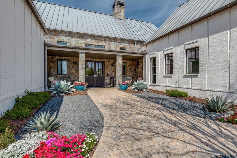 Property entrance featuring a chimney, a standing seam roof, and stone siding