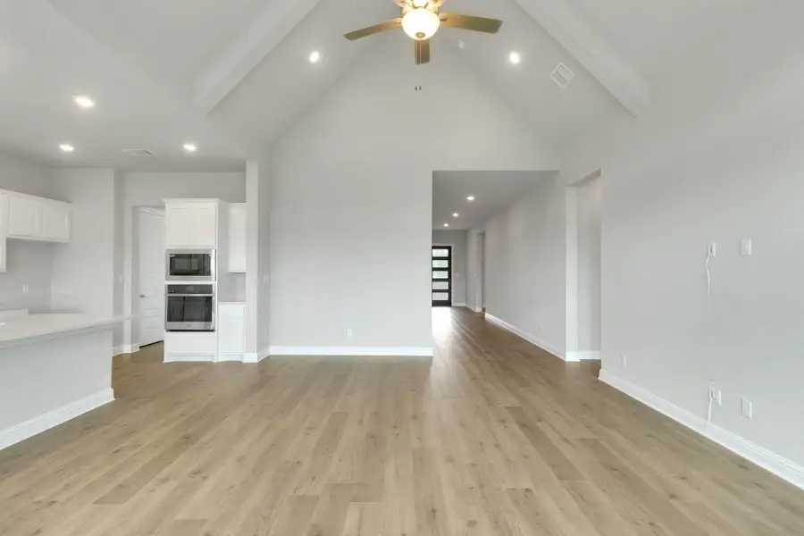 Unfurnished living room featuring visible vents, ceiling fan, high vaulted ceiling, and beamed ceiling