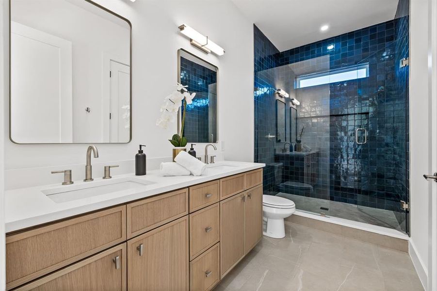 Bathroom with tile patterned floors, vanity, toilet, and a shower with shower door