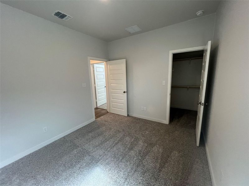 A well-lit bedroom features plush gray carpet and a convenient walk-in closet.