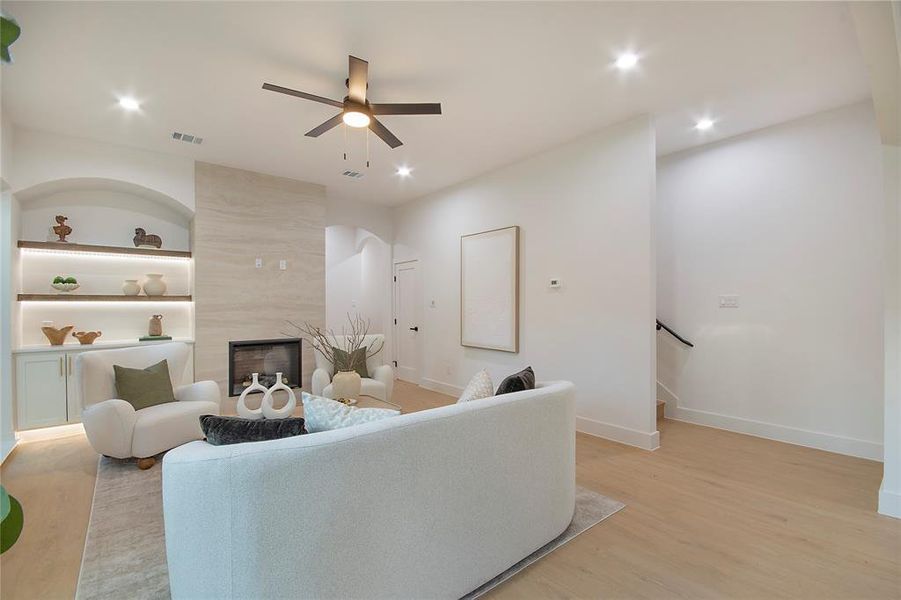 Living room with light wood-style flooring, a fireplace, built in features, a ceiling fan, and recessed lighting