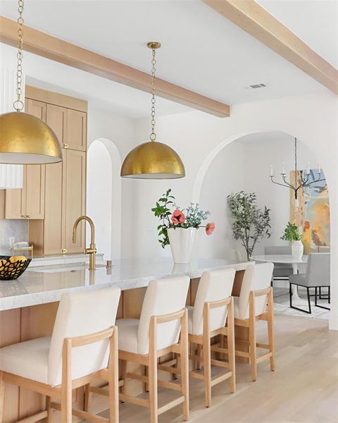 Kitchen with light hardwood / wood-style floors, light brown cabinets, decorative backsplash, and pendant lighting