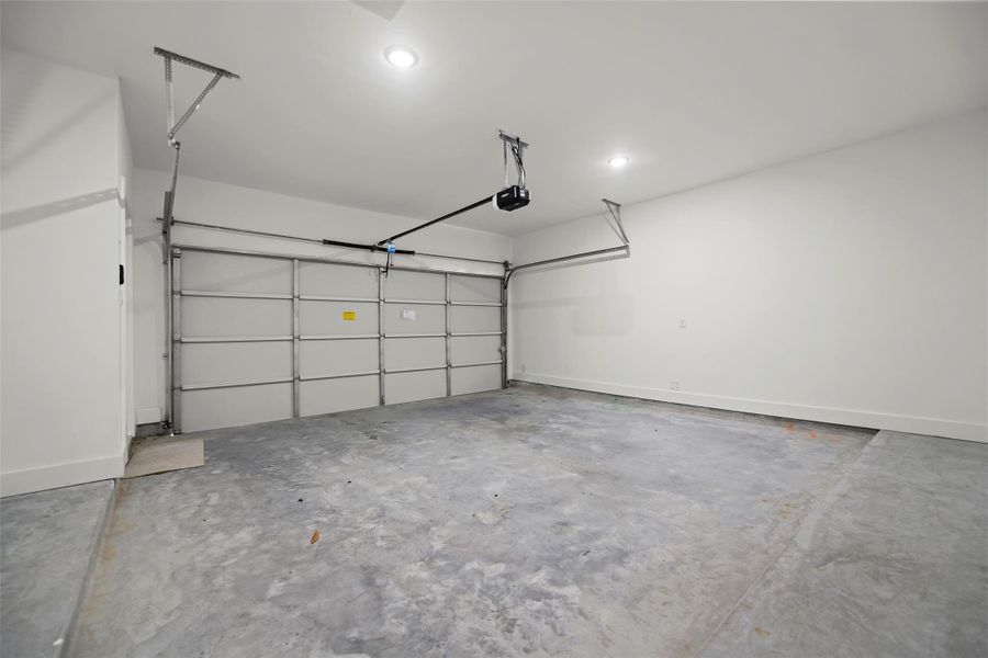 This is a spacious, clean garage with a concrete floor and WiFi automatic door opener, offering ample room for parking and storage.