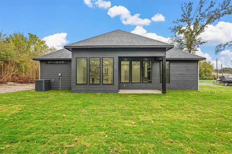 Rear view of property featuring a yard and central air condition unit