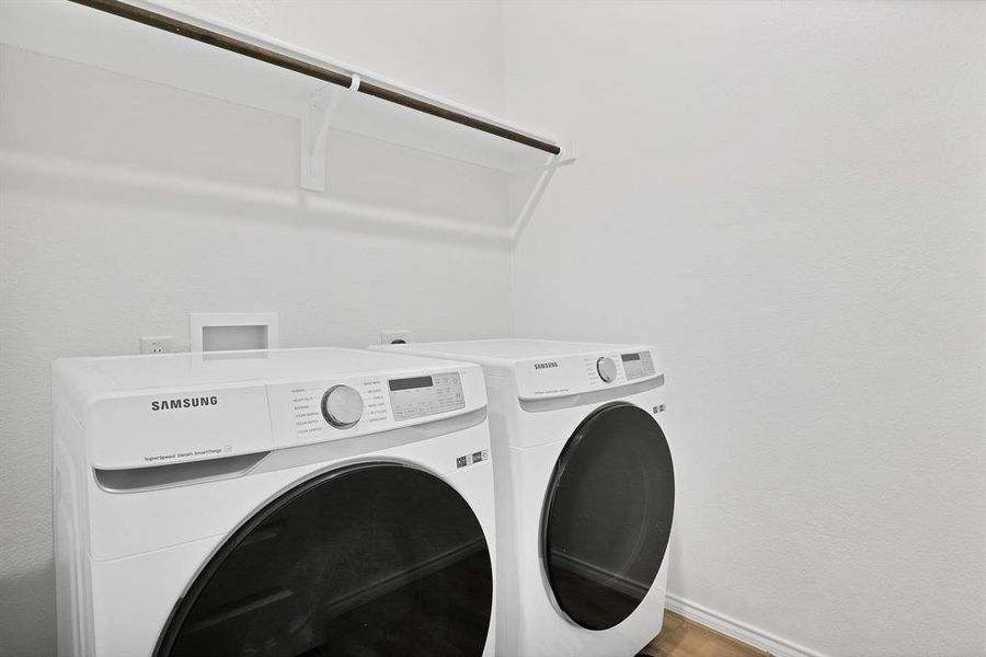 Washroom featuring hardwood / wood-style flooring and washing machine and clothes dryer