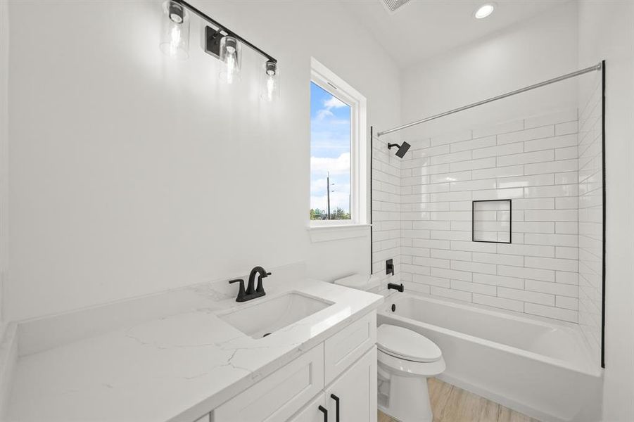 This bathroom is complete with tile floors, soft closing drawers, granite countertops, recessed lighting, and a shower/tub combo. Photos are from a similar unit in the development.