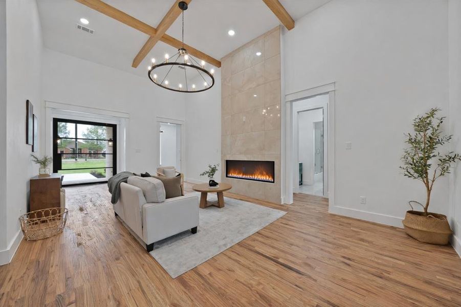 Living area featuring hardwood floors, a vaulted ceiling with exposed beams, a modern fireplace with a tiled surround, and a large glass door providing natural light