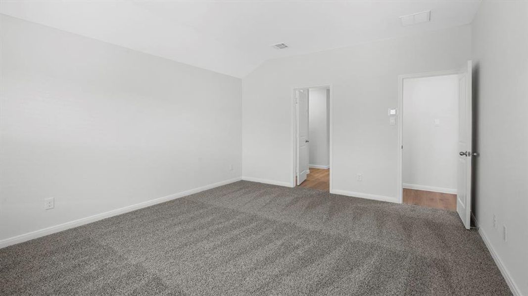 Spacious room featuring neutral carpeting, light-colored walls, and a vaulted ceiling Spacious room featuring neutral carpeting, light-colored walls, and a vaulted ceiling