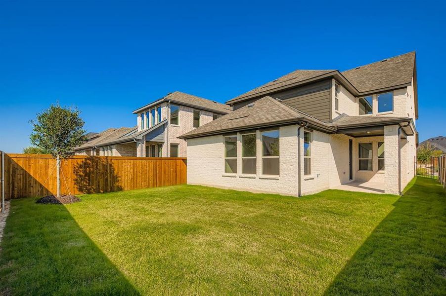 Back of house with a fenced backyard, a shingled roof, a patio, and brick siding