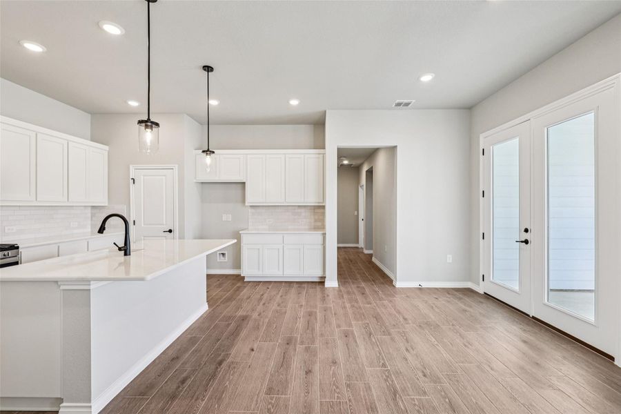 Kitchen featuring light countertops, tasteful backsplash, light wood-type flooring, white cabinets, and recessed lighting Kitchen featuring light countertops, tasteful backsplash, light wood-type flooring, white cabinets, and recessed lighting