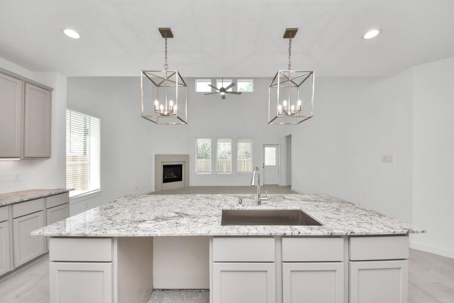 This kitchen is truly a chef's dream! This haven Boasts high ceilings, recessed & pendant lighting, stained wood cabinets, granite countertops, stainless steel appliances, a modern tile backsplash.  All of this overlooks your expansive family room, creating a perfect space for culinary delights and family gatherings. Sample photo of completed home with similar floor plan. Actual colors and selections may vary.