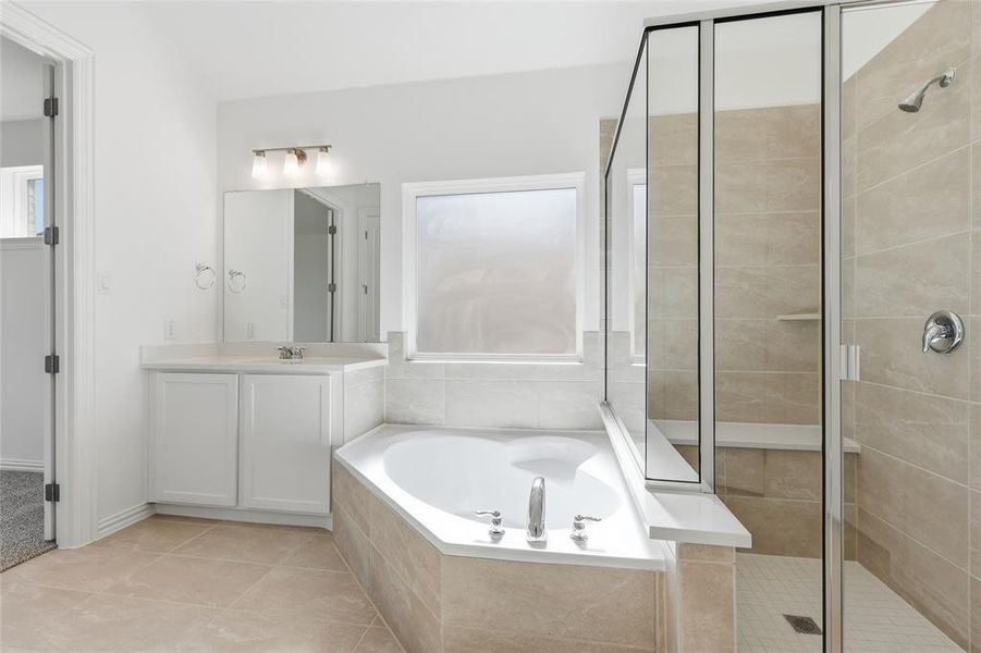 Bathroom with a stall shower, a bath, vanity, and light tile patterned floors