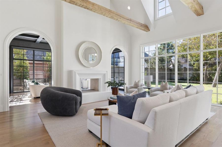 Living room featuring high vaulted ceiling, light wood-type flooring, healthy amount of natural light, beamed ceiling, and recessed lighting