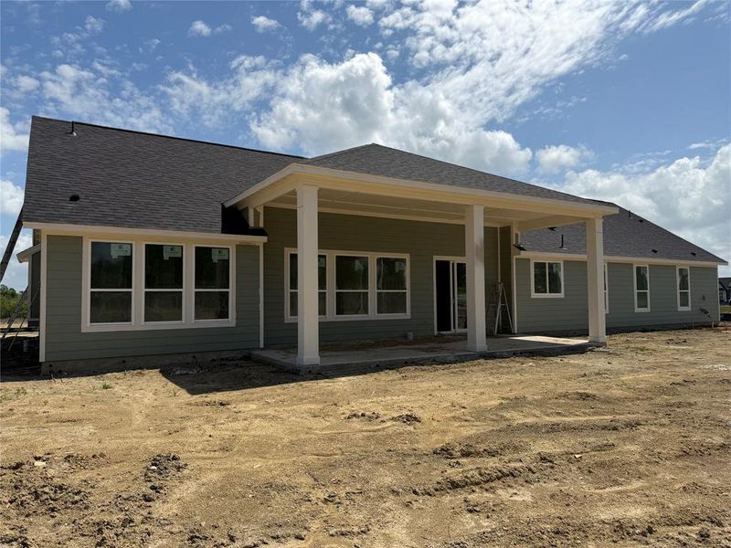 Rear view of property featuring a patio and roof with shingles