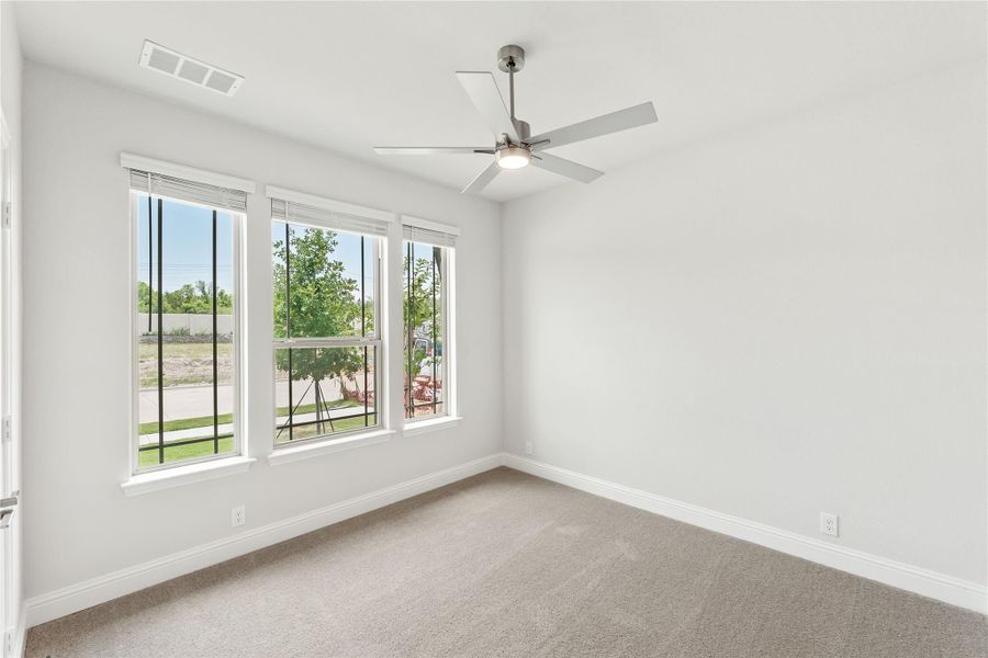 Empty bedroom with carpet flooring, ceiling fan, and three windows with outdoor views Empty bedroom with carpet flooring, ceiling fan, and three windows with outdoor views