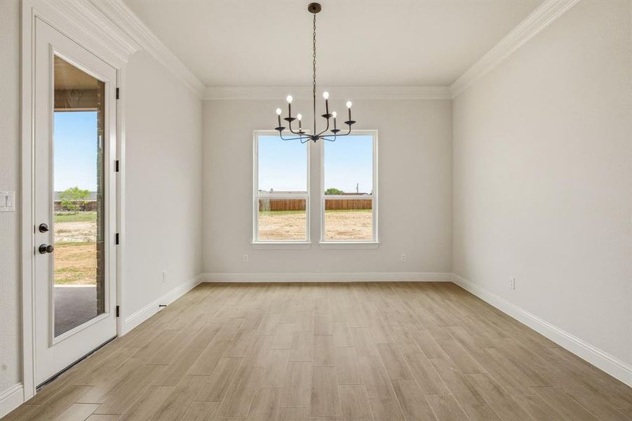 Unfurnished dining area with hanging lights, wood finish floors, and ornamental molding