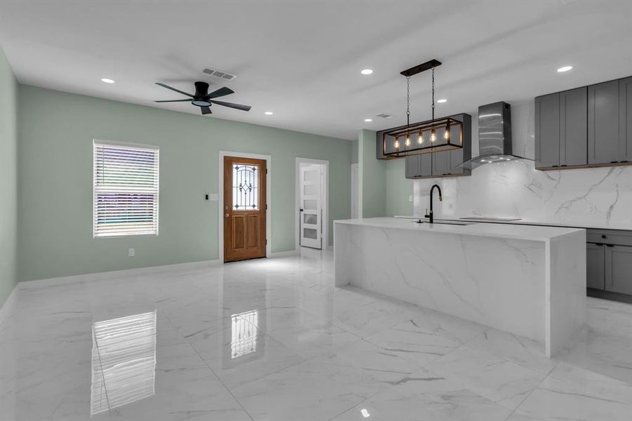 Kitchen with gray cabinets, light marble finish flooring, recessed lighting, tasteful backsplash, and a center island with sink Kitchen with gray cabinets, light marble finish flooring, recessed lighting, tasteful backsplash, and a center island with sink