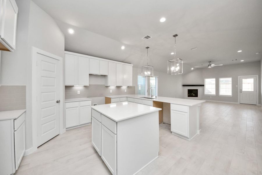 This generously spacious kitchen is a dream realized! With a massive granite island, high ceilings, soft close cabinets, granite countertops, stainless steel appliances, a sleek tile backsplash, recessed lighting, and an extended counter area, it offers both style and practicality. All this opens up to the expansive family room, creating a perfect hub for gatherings. Sample photo of completed home with similar floor plan. Actual colors and selections may vary.