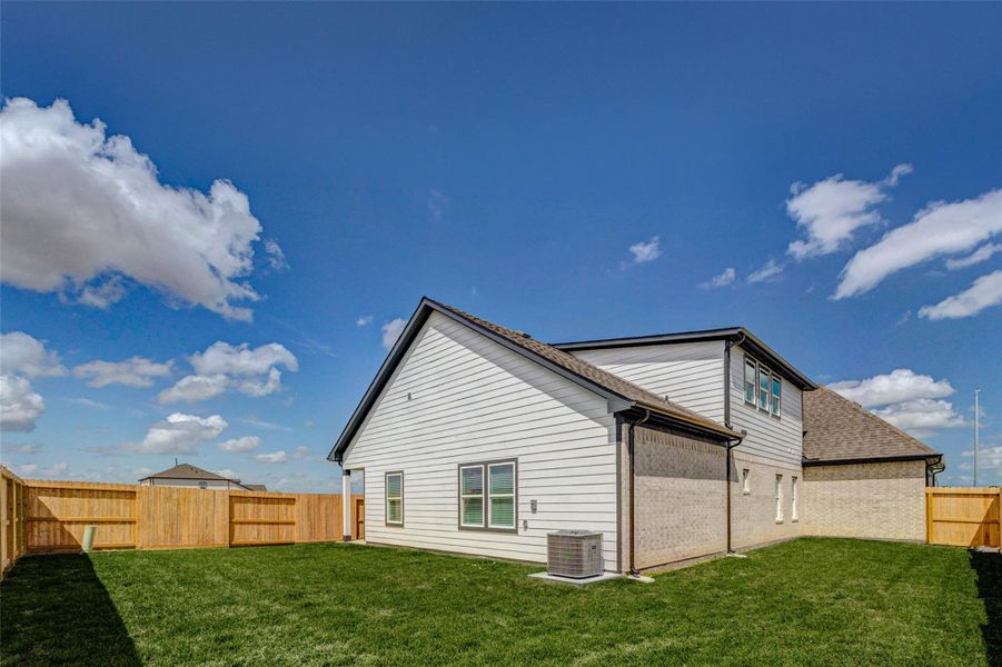 This wide-angle view highlights the generous backyard and side exterior of the home, offering ample green space and privacy. The fully fenced yard creates a secure and inviting environment, while the home’s exterior design blends modern siding with classic elements. With room to add a pool, play area, or outdoor kitchen, this backyard provides endless possibilities for customization and enjoyment.