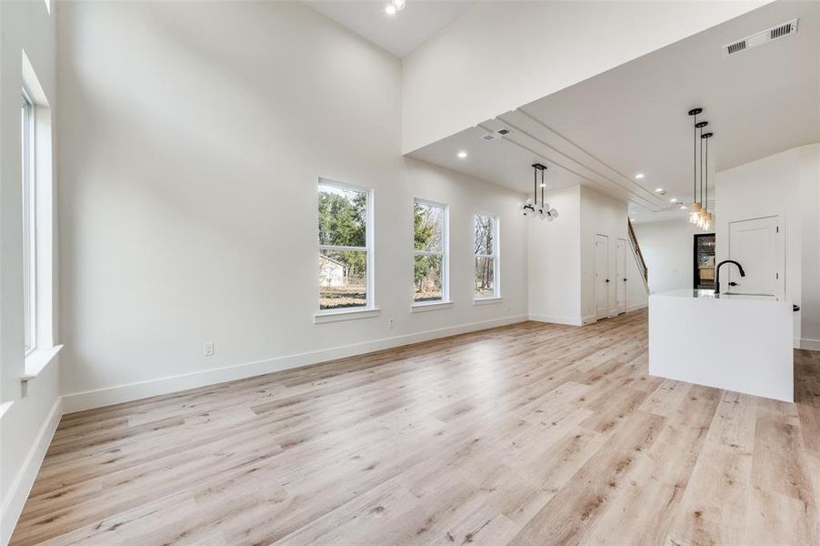 Unfurnished living room with light wood-style floors, a high ceiling, and recessed lighting