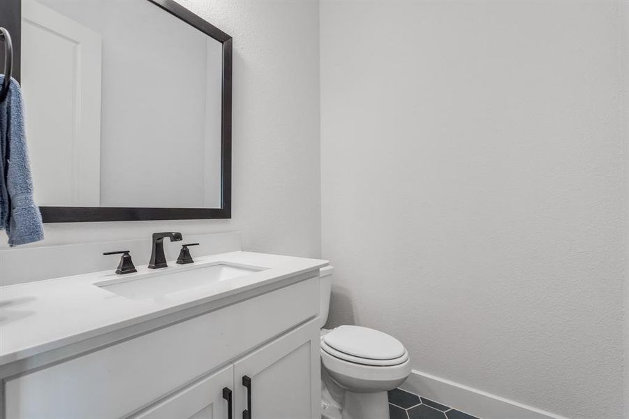 Bathroom with toilet, vanity, and tile patterned floors