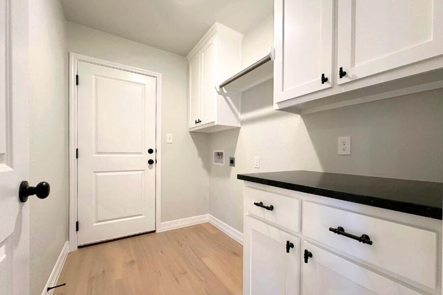 Laundry area featuring light wood finished floors, cabinet space, hookup for a washing machine, and hookup for an electric dryer