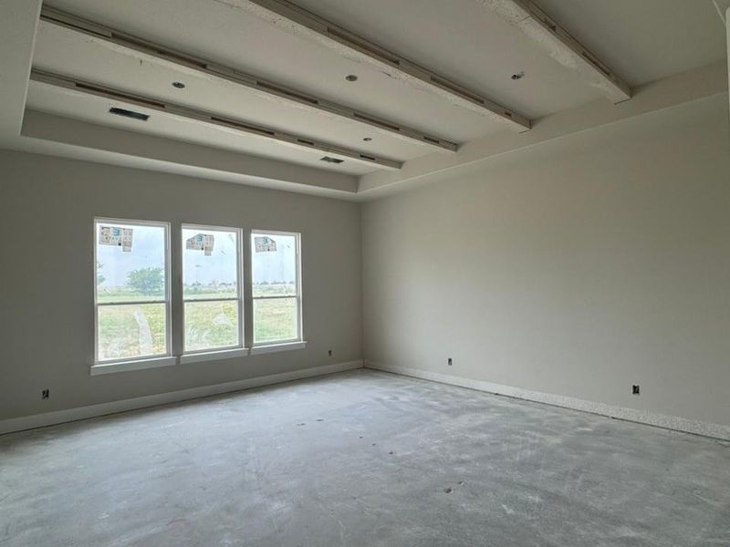 Spacious interior featuring a multi-layered tray ceiling with recessed lighting and three large windows