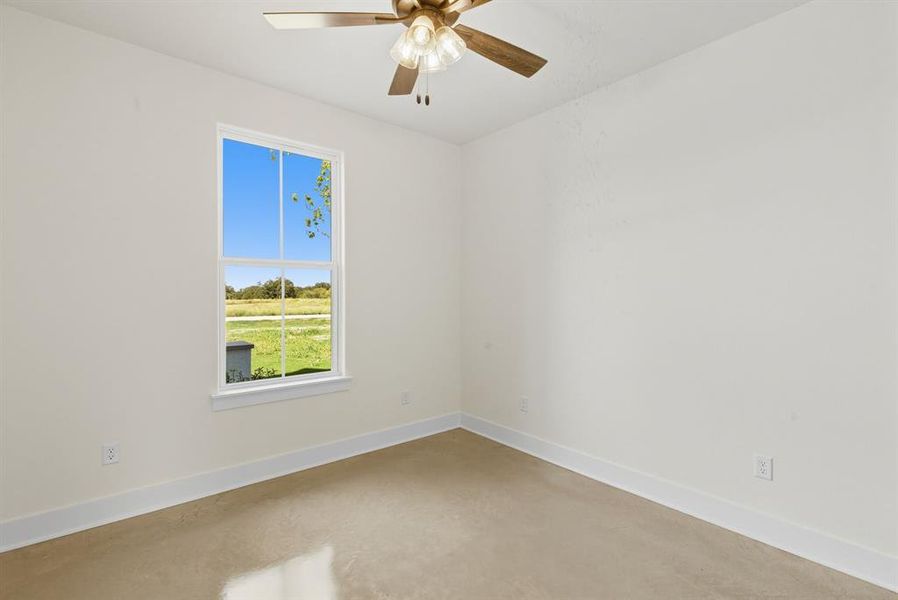 Unfurnished room with finished concrete flooring and ceiling fan
