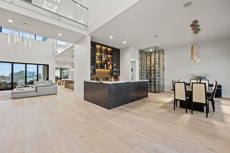 Bar with a towering ceiling, decorative light fixtures, and light wood-type flooring