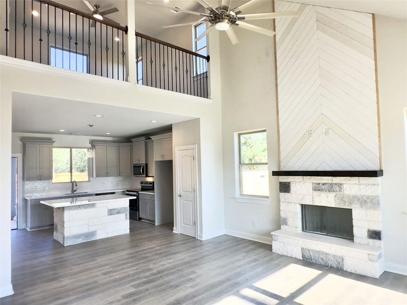 Kitchen with gray cabinetry, a ceiling fan, stainless steel appliances, open floor plan, and a towering ceiling Kitchen with gray cabinetry, a ceiling fan, stainless steel appliances, open floor plan, and a towering ceiling