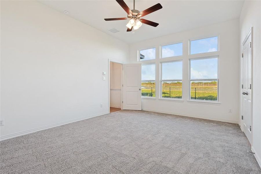 Carpeted spare room featuring ceiling fan and a towering ceiling