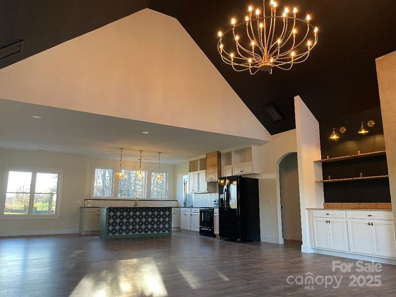 The grand view of the family room-kitchen-dining area with special lighting and ceiling features along with open shelving built-in by the fireplace