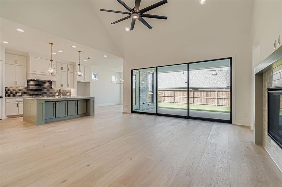 Unfurnished living room with recessed lighting, high vaulted ceiling, light wood-type flooring, a tile fireplace, and ceiling fan Unfurnished living room with recessed lighting, high vaulted ceiling, light wood-type flooring, a tile fireplace, and ceiling fan