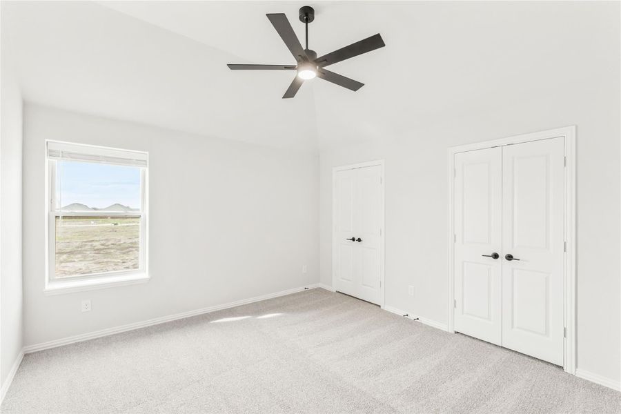 Empty bedroom with carpet, ceiling fan, double closet doors, and a window with desert views Empty bedroom with carpet, ceiling fan, double closet doors, and a window with desert views