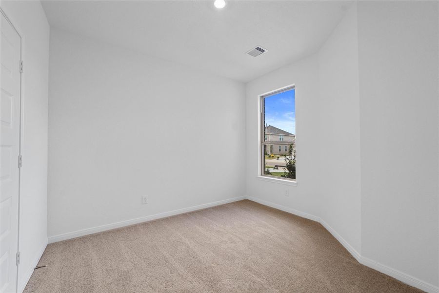 Tucked peacefully in the front of the home is this secondary bedroom. It features custom paint, a large window, and a generously sized closet.