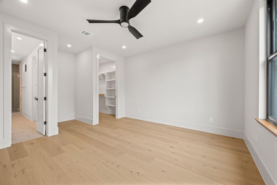 Gleaming hardwood floors and recessed lighting anchor this quiet bedroom space.