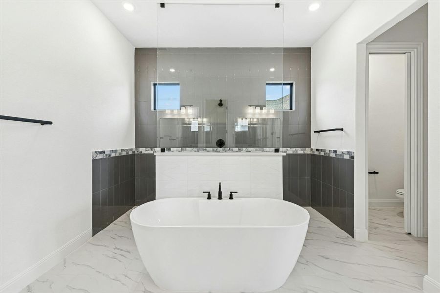 Full bathroom featuring a walk in shower, a freestanding tub, tile walls, and recessed lighting