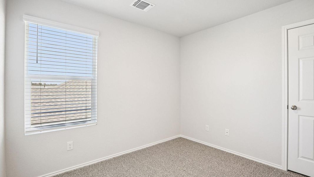 Bright room featuring a large window with blinds, neutral wall paint, and gray carpet flooring