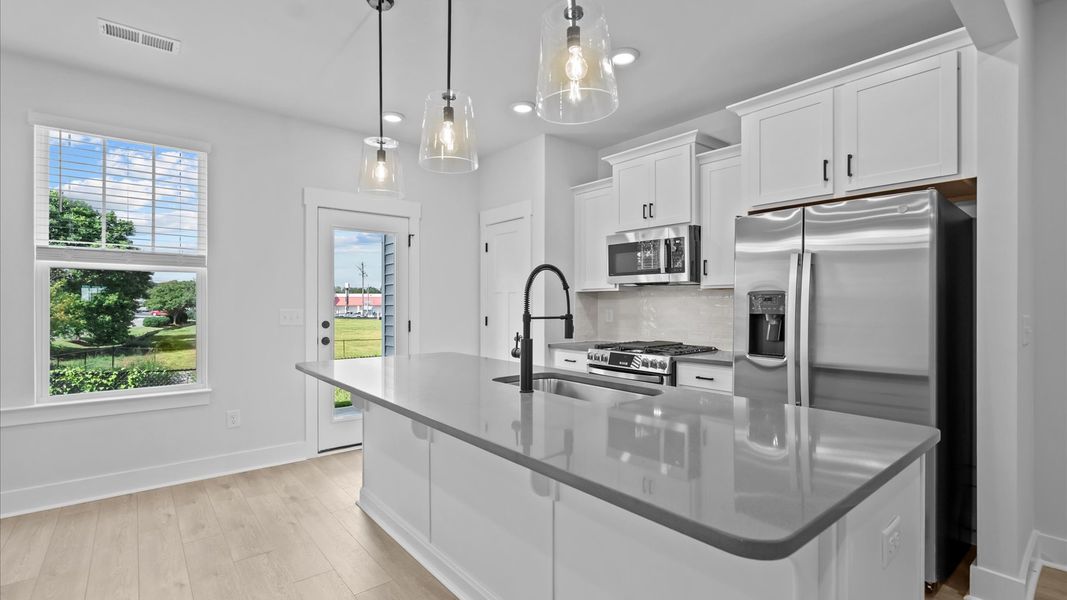 Highly skilled kitchen design includes a 9-foot island, quartz countertops, and stylish pendant fixtures Highly skilled kitchen design includes a 9-foot island, quartz countertops, and stylish pendant fixtures