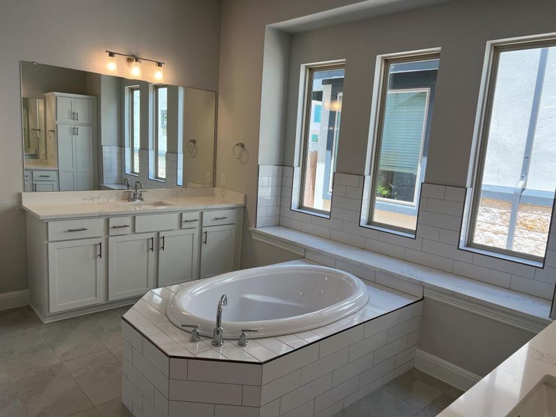 Bathroom featuring a garden tub, vanity, and tile patterned flooring