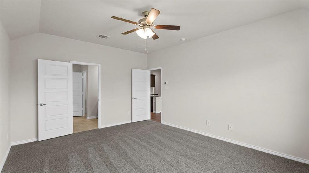 Spacious room featuring vaulted ceilings, light gray wall paint, and gray carpet flooring