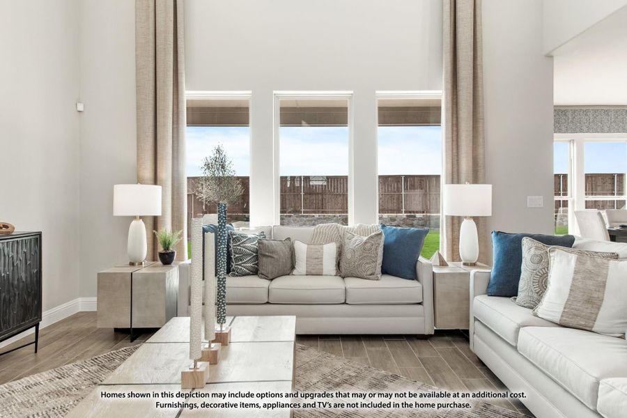 Living room with high ceilings, large windows, light gray sofas, and blue accent pillows on wood-look floors Living room with high ceilings, large windows, light gray sofas, and blue accent pillows on wood-look floors