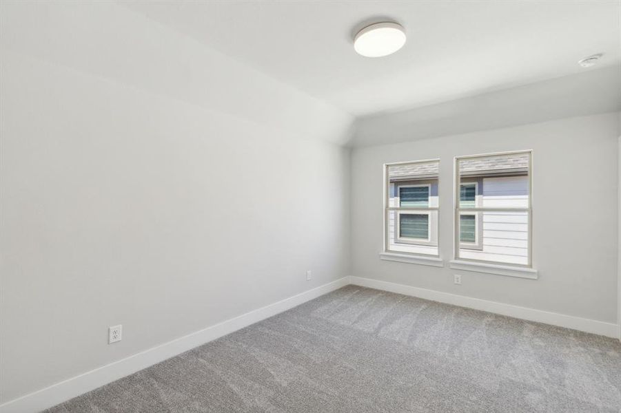 Carpeted empty room with lofted ceiling