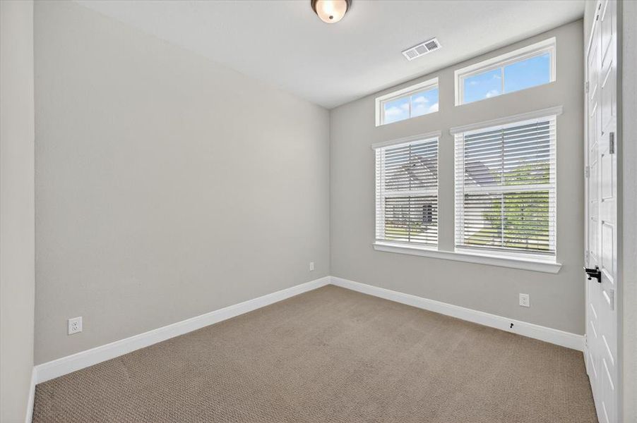 Neutral-toned room featuring a multi-paneled door, recessed ceiling light, and light brown carpet flooring Neutral-toned room featuring a multi-paneled door, recessed ceiling light, and light brown carpet flooring