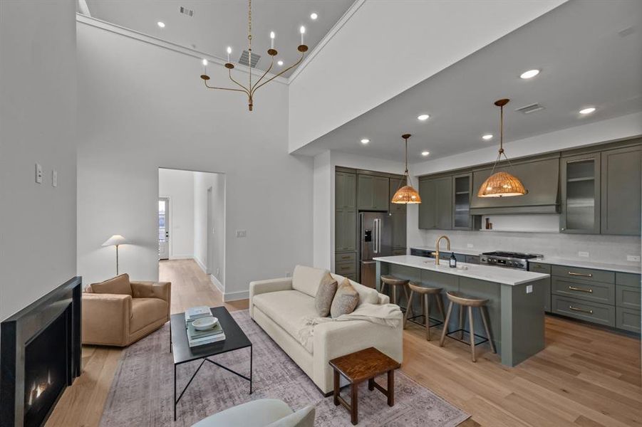 Living room featuring sink, light hardwood / wood-style floors, and a towering ceiling