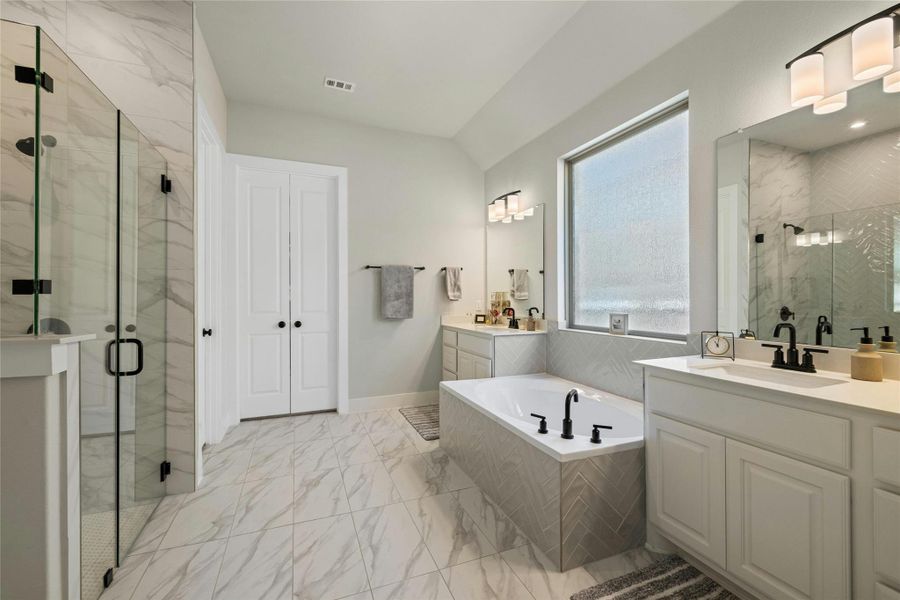 Bathroom featuring marble look tile flooring, a marble finish shower, two vanities, and a garden tub Bathroom featuring marble look tile flooring, a marble finish shower, two vanities, and a garden tub