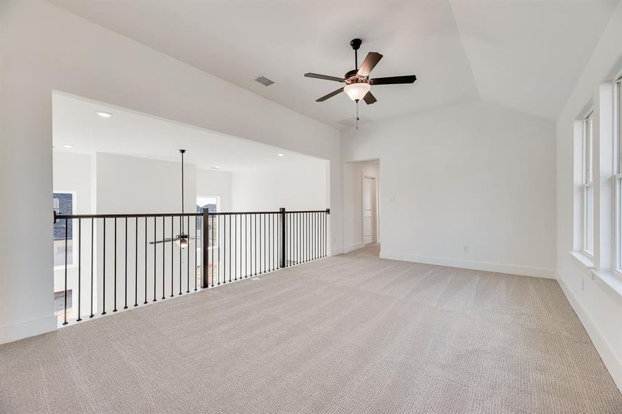 Unfurnished room featuring a ceiling fan, light colored carpet, and vaulted ceiling